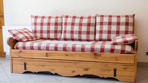 A wooden sofa with checkered upholstery and storage drawers. - Homerez - Apartment in Saint-Crepin (Saint-Crepin)