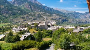 A mountainous village with a prominent church, surrounded by greenery and rocky terrain. - Homerez - Apartment in Saint-Crepin (Saint-Crepin)