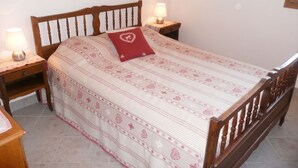 A neatly made bed with a patterned bedspread, two bedside lamps, and a wooden headboard. - Homerez - Apartment in Saint-Crepin (Saint-Crepin)