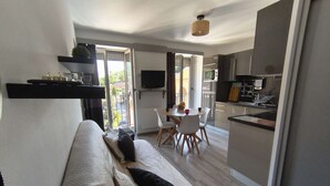 Ein modernes Apartment mit Sofa, Esstisch, Stühlen, Küchenzeile und einem Balkon mit Blick.