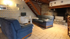 A cozy living room with a fireplace, a television, and a staircase leading upstairs. - Charming house in Lingreville near beach, for 5 pers, with Wi-Fi and pets allowed (Lingreville)