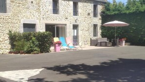 A stone building with a paved driveway, outdoor seating, and a large umbrella. - Charming house in Lingreville near beach, for 5 pers, with Wi-Fi and pets allowed (Lingreville)