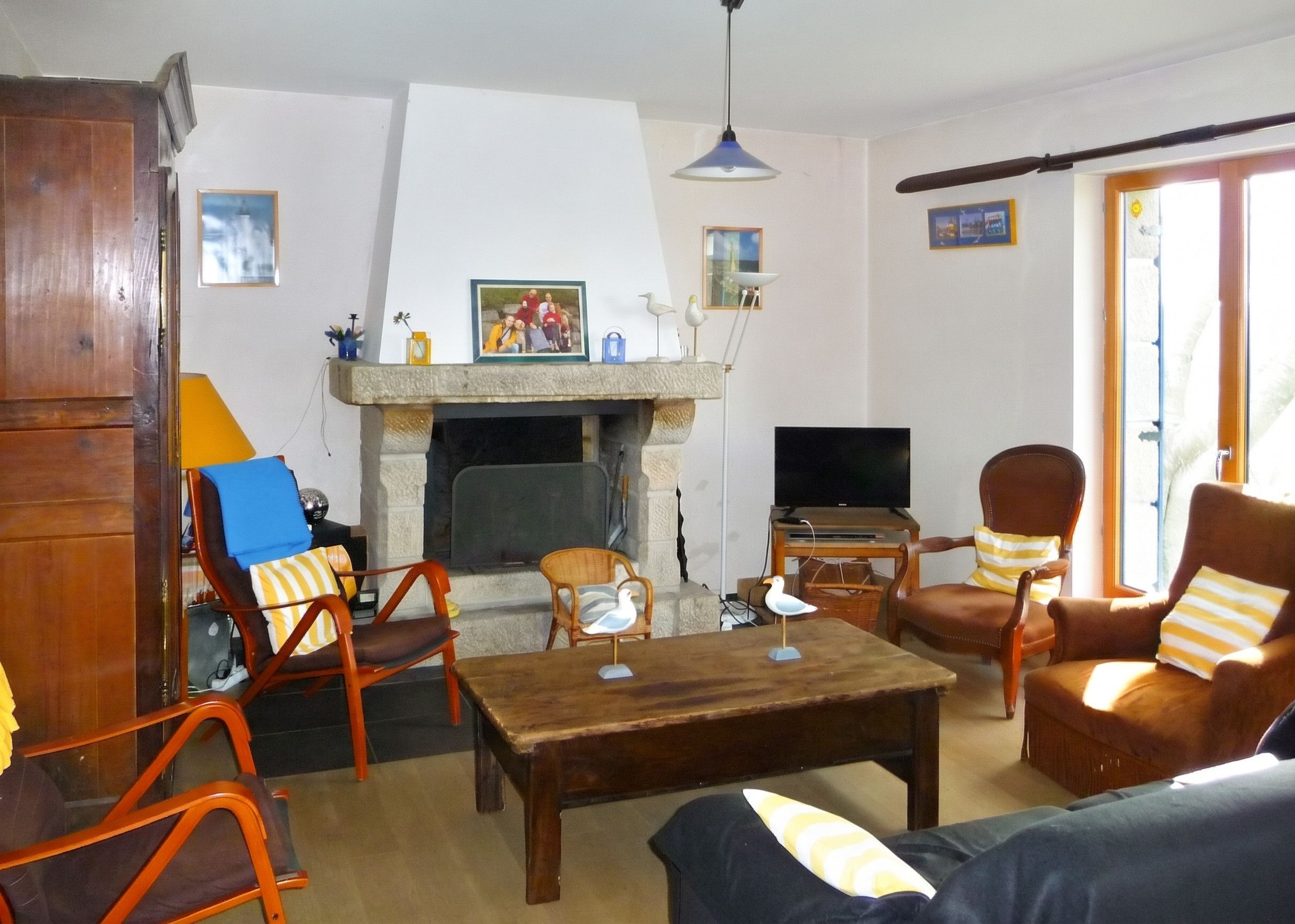 A living room with a fireplace, wooden furniture, a television, and a door leading outside.