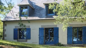 A two-story house with a gabled roof, blue shutters, and a small porch area. - Homerez - House in Plougrescant. (Plougrescant)