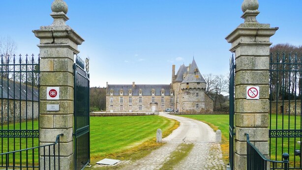 A stone gate leading to a large, historic building with multiple towers and a well-maintained lawn. - Homerez - House in Plougrescant. (Plougrescant)