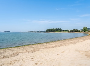 A sandy beach with calm water, a clear sky, and distant landforms. - Homerez - House in Plougrescant. (Plougrescant)