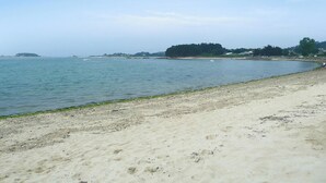 A beach with a sandy shore and calm water. - Homerez - House in Plougrescant. (Plougrescant)