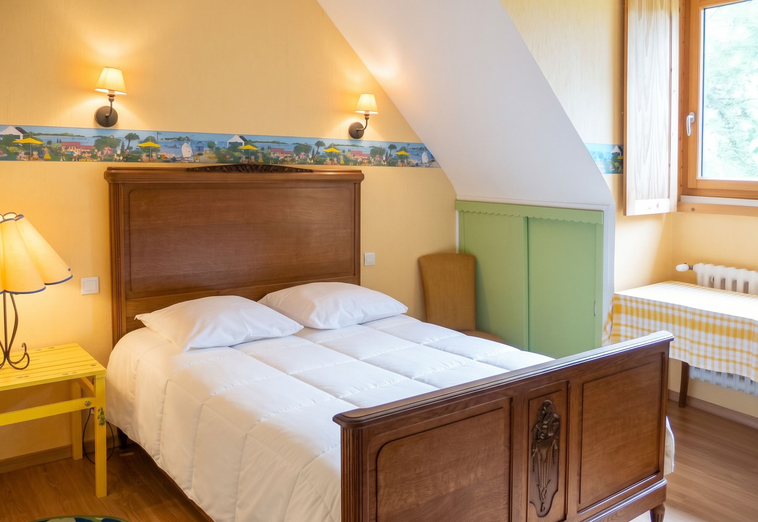 A bedroom with a wooden bed, two wall-mounted lamps, a small table with a lamp, and a window with a view.