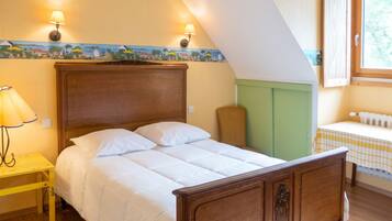 A bedroom with a wooden bed, two wall-mounted lamps, a small table with a lamp, and a window with a view.