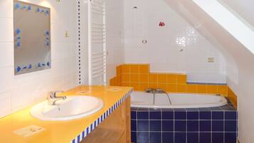 A bathroom with a sink, mirror, towel rack, and bathtub.