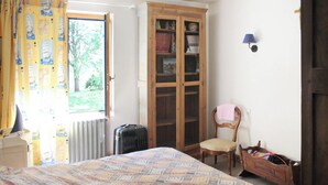 A bedroom with a bed, a wooden wardrobe, a chair, and a radiator. - Homerez - House in Plougrescant. (Plougrescant)