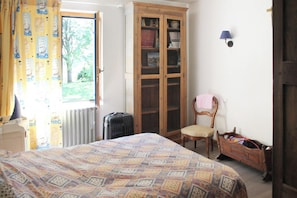 A bedroom with a bed, a wooden wardrobe, a chair, and a radiator. - Homerez - House in Plougrescant. (Plougrescant)