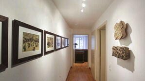 A hallway with framed artworks on the left and two textured sculptures on the right. - lang 80m2 city center          3br (Colmar)