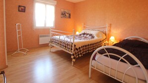 A bedroom with two beds, a window, a radiator, and a ceiling light. - Independent single-storey house near dunes, pets allowed (Les Moitiers-d'Allonne)