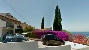 Ein Wohngebiet mit einem Haus, parkenden Autos und Blick auf das Meer.