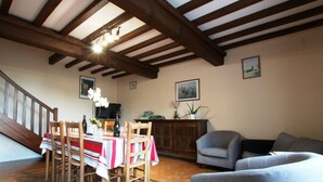 A dining area with a wooden table and chairs, a television, and a cabinet with decorative items.