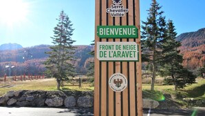A wooden sign with 'BIENVENUE' and 'FRONT DE NEIGE DE L'ARAVET' indicating a welcome area.