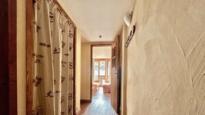 A hallway with a wooden floor, a door at the end, and a wall with a textured pattern.