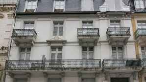 A multi-story building with a symmetrical facade, featuring evenly spaced windows and decorative iron railings on the balconies. - Duplex 3-Room 6-Person with Balconies, Near Ski Lifts and Amenities, Heart of Cauterets (Cauterets)