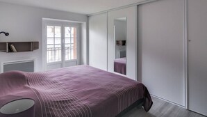 A bedroom with a bed, a wardrobe, a mirror, and a window. - Duplex 3-Room 6-Person with Balconies, Near Ski Lifts and Amenities, Heart of Cauterets (Cauterets)