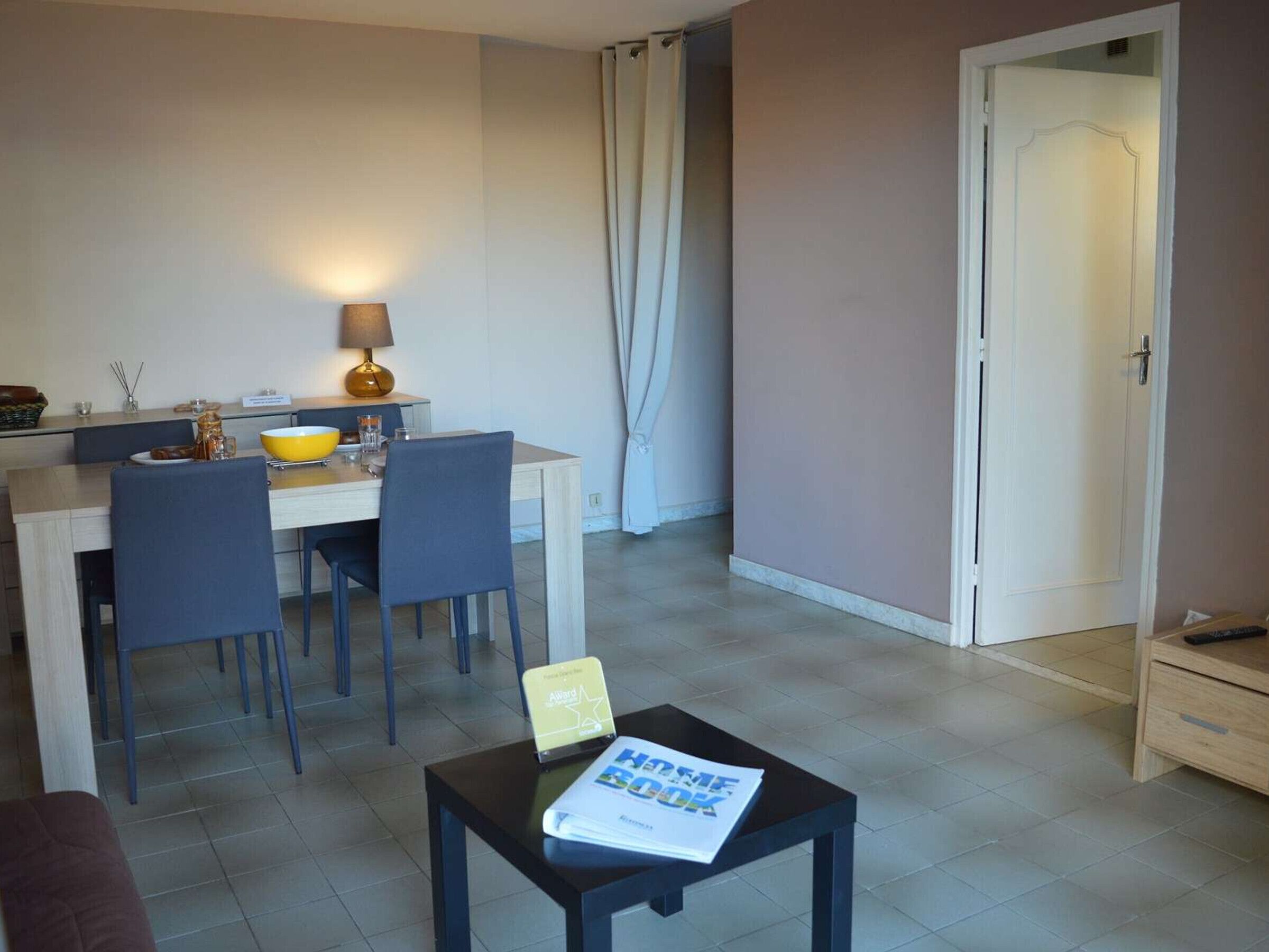 A dining area with a table, chairs, a lamp, and a magazine on a small table.