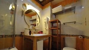 Ein Badezimmer mit einem Holzbidet, einem runden Spiegel, einer Toilette und einer Duschkabine.
