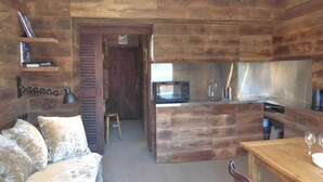 A rustic cabin interior with a wooden interior, a kitchenette, a sofa, and a dining table.