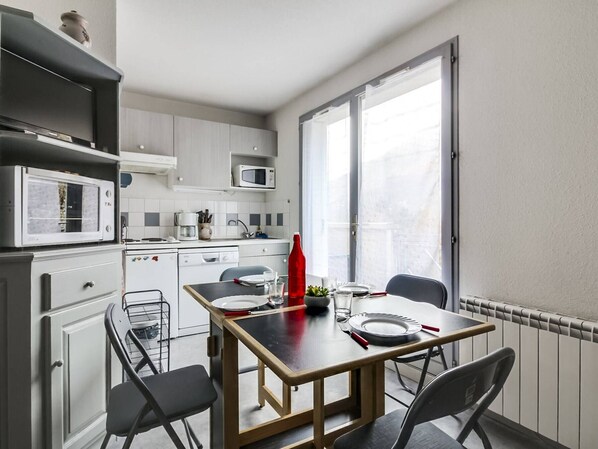 Una cocina compacta con comedor, armarios blancos, un microondas y ventana con vistas.