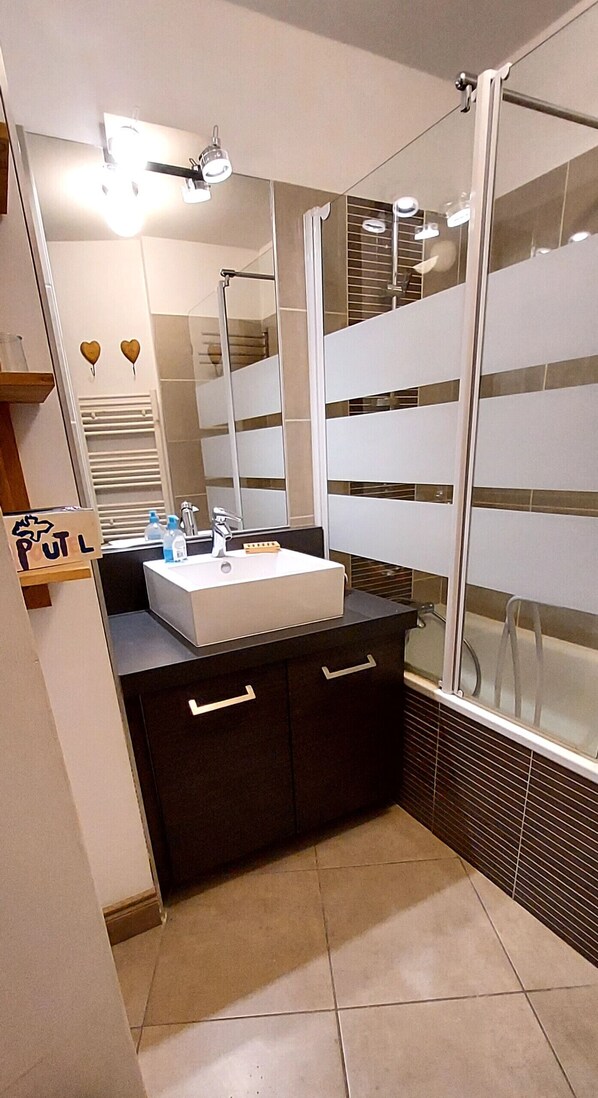 A modern bathroom with a white sink, dark cabinetry, a large mirror, and a shower area. - D105 - 58 m2 - 3P - 6/8 pers (Prapoutel)