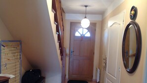 A hallway with a wooden door, a mirror, and a ceiling light fixture.