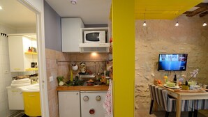 A compact kitchen with a microwave, sink, and a dining area with a table and chairs. - D3DG Summer Sweetness (Paris)