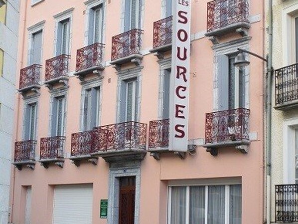 A building with multiple balconies and a vertical sign with text.