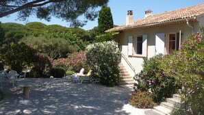 A house with a tiled roof, a staircase leading to the entrance, and a garden with chairs and flowers. - Villa L'abri Cotier - Sainte-maxime (SAINTE MAXIME)
