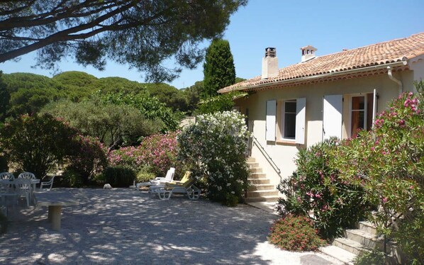 A house with a tiled roof, a staircase leading to the entrance, and a garden with chairs and flowers. - Villa L'abri Cotier - Sainte-maxime (SAINTE MAXIME)