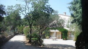 A courtyard with a building, a gravel path, and a table with chairs. - Villa L'abri Cotier - Sainte-maxime (SAINTE MAXIME)