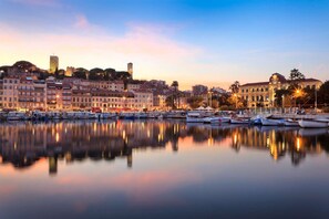 A marina with boats docked, a historic building with a clock tower, and a calm waterfront at dusk. - 5 min walk to the sea, the Croisette and the Palais des Festivals (Cannes)