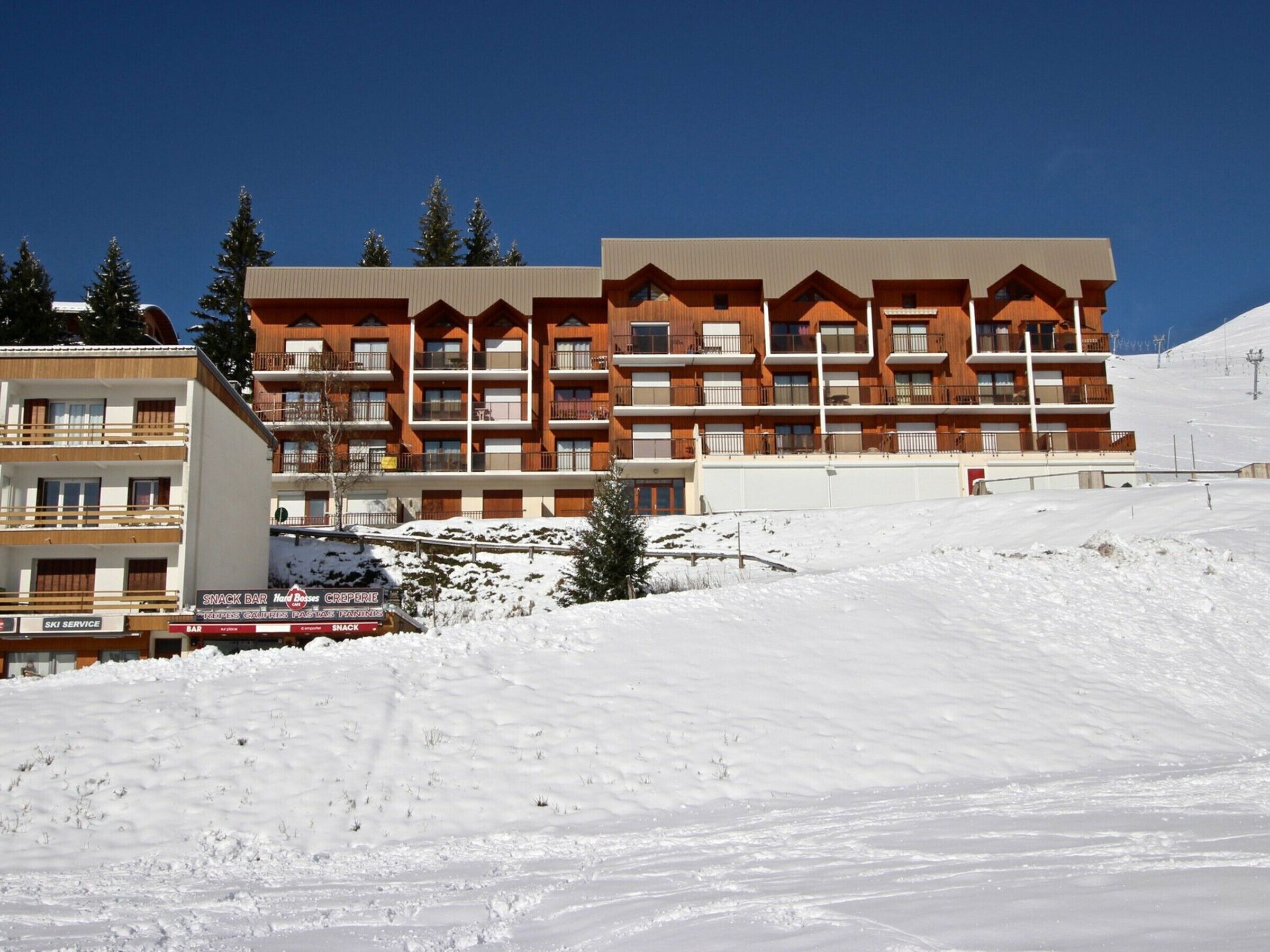 Een meerhoog hotel met balkons, ski service en een snackbar.