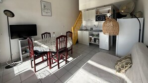 A compact living space with a dining area, kitchenette, and a TV.