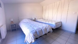 A bedroom with two beds, a bedside table, a lamp, and a wall-mounted decoration.