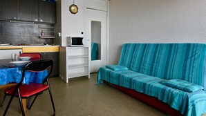 Ett kompakt bostadsutrymme med ett litet kök, en matplats och en soffa.