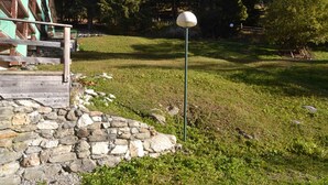 A stone wall, a wooden bench, and a spherical object on a grassy slope with trees in the background. - Studio for 5, ski-in/ski-out, pets allowed, Arcs 1800 (Les Arcs 1800)