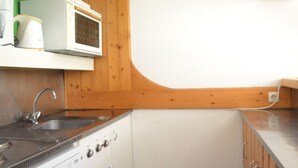 A compact kitchen with a sink, stove, microwave, and wooden cabinets. - Studio for 5, ski-in/ski-out, pets allowed, Arcs 1800 (Les Arcs 1800)