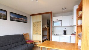 A compact living space with a sofa, a small table, a kitchenette with a microwave, and a wooden cabinet. - Cozy 2-Room Apartment for 4 with South-Facing Balcony, Near Ski Lifts and Shops, L'Alpe d'Huez (Huez)