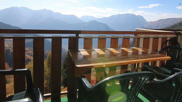 A wooden table and chairs on a balcony with a mountain view. - Cozy 2-Room Apartment for 4 with South-Facing Balcony, Near Ski Lifts and Shops, L'Alpe d'Huez (Huez)