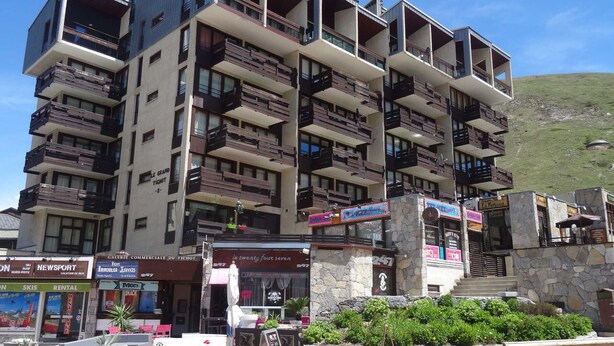 A multi-story hotel with balconies, outdoor seating, and a stone facade. - Cozy 2-room apartment for 5 in Tignes, close to slopes and shops (Tignes)