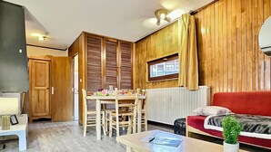 A compact room with a dining table, wooden walls, a red sofa, and a small window. - Cozy 2-room apartment for 5 in Tignes, close to slopes and shops (Tignes)