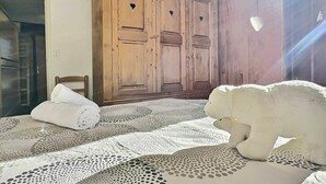 A bedroom with a large wooden wardrobe, a white bed with a lace cover, and a white stuffed animal on the bed. - Cozy 2-room apartment for 5 in Tignes, close to slopes and shops (Tignes)