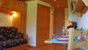 Una habitación acogedora con techo de madera, un sofá, una mesa de comedor con sillas y una puerta de madera.