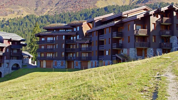 Un hotel de varios pisos con balcones, con montañas al fondo.