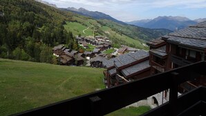 Un pueblo tradicional con casas de madera, un camino serpenteante y montañas al fondo.